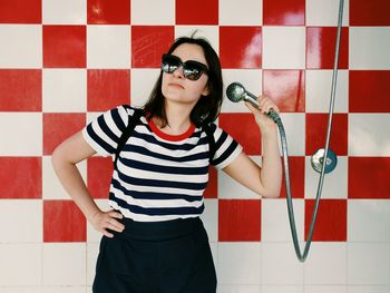 Young woman holding handheld shower