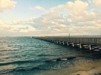 Pier on sea against cloudy sky