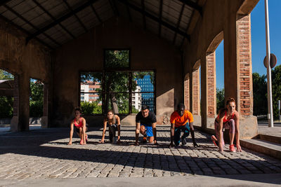 Group of diverse sportspeople standing in crouch start position ready for run during training in urban area of city