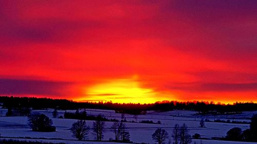 Scenic view of snowcapped landscape against orange sky
