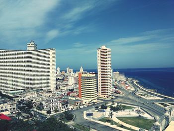 High angle view of city buildings by sea against sky