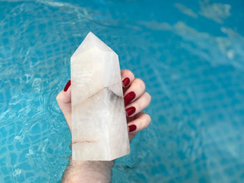 Midsection of person holding crystal in swimming pool