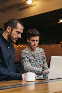 Friends working on laptop while sitting in cafe