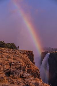 Scenic view of rainbow over rocks against sky