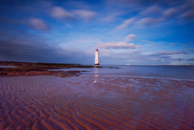 Lighthouse by sea against sky