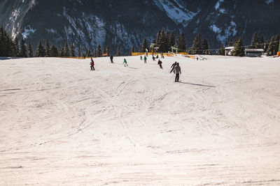 People skiing on snow covered against mountain