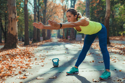 Full length of woman exercising in park during autumn