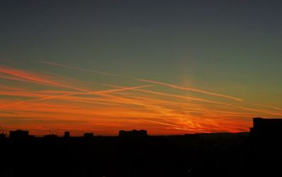 Silhouette cityscape against sky at sunset