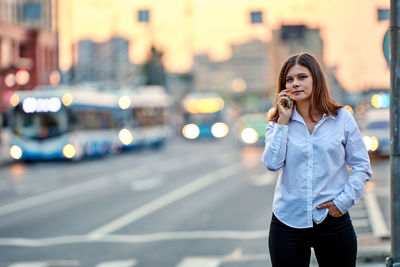 Portrait of young woman talking on phone on street