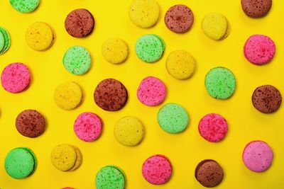 High angle view of colorful macaroons on yellow background