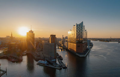 Scenic view of river and buildings against sky during sunset