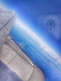 Aerial view of aircraft wing over sea against sky