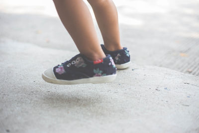 Low section of girl walking on footpath