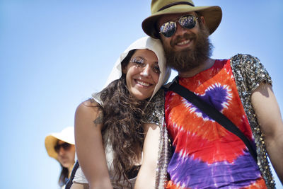 Low angle view of cheerful man and woman standing against clear sky at traditional event