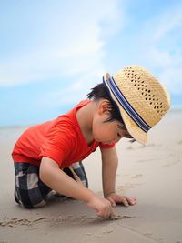 Cute boy writing on sand while playing at beach