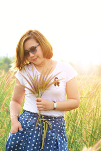 Woman holding plants on field