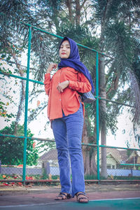 Portrait of woman standing against trees