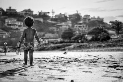 Rear view of boy standing in water
