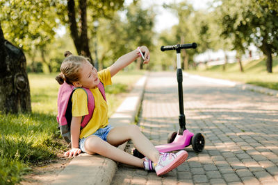 Portrait of a little beautiful schoolgirl girl using a mobile phone and taking a selfie