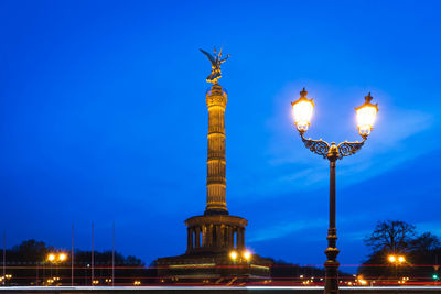 Low angle view of illuminated street light against blue sky
