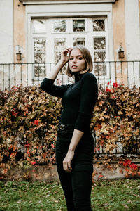 Portrait of beautiful young woman standing against building