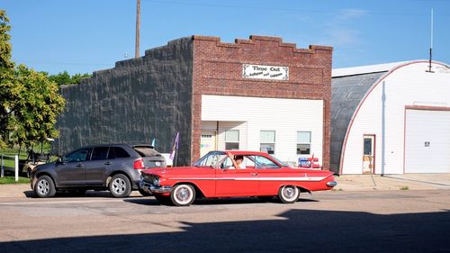 Cars on street by buildings against sky