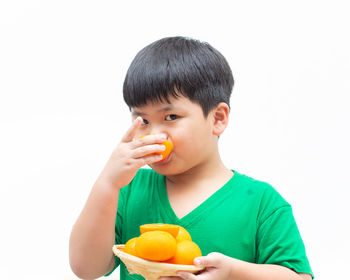 Portrait of boy eating food against white background