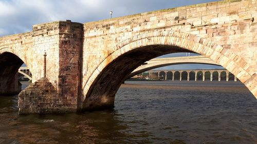 Arch bridge over river against sky