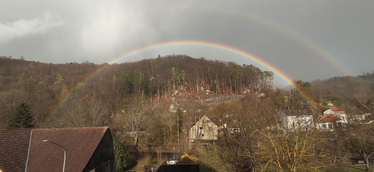 rainbow, tree, nature, plant, beauty in nature, architecture, double rainbow, scenics - nature, sky, multi colored, environment, built structure, cloud, building exterior, landscape, house, no people, building, land, tranquility, idyllic, day, outdoors, tranquil scene, natural phenomenon, sunlight, mountain, wet