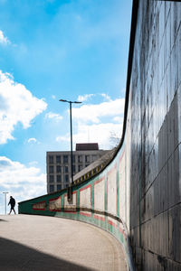 Curved wall against blue sky framing lone person