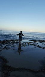 Silhouette man standing on beach against clear sky