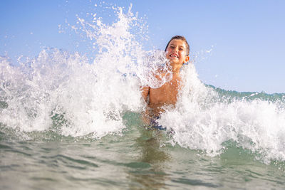 Funny kid playing with waves on the beach