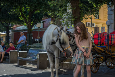 Young woman standing next to horse carriage on the street