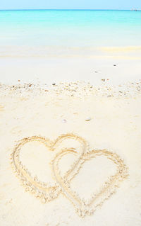 Close-up of heart shape on sand at beach