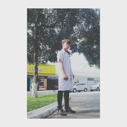 Portrait of young man standing by tree in city