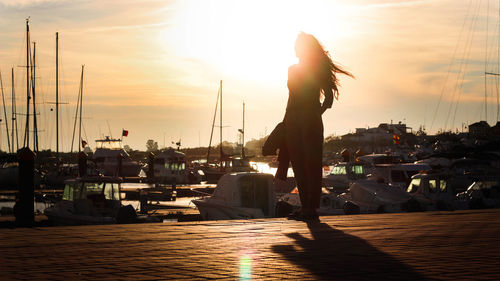 Silhouette of harbor against sky during sunset