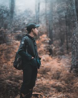 Side view of man looking away in forest