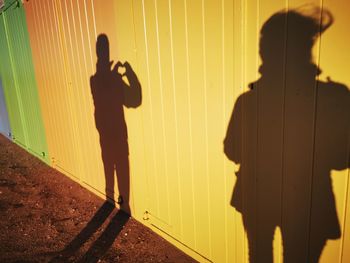 Silhouette people standing against yellow wall