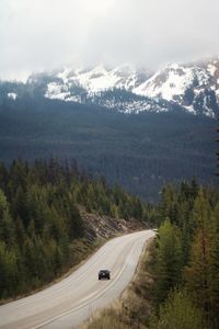 Car on winding road amidst trees and mountains 