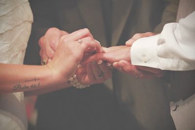 Midsection of man standing by bride and bridegroom holding hands