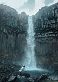 Man standing on rock against waterfall