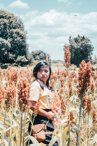 Portrait of smiling woman on field against sky