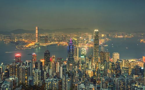 Illuminated modern buildings in city against sky