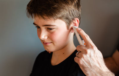 Tween boy getting temperature taken with an ear thermometer.