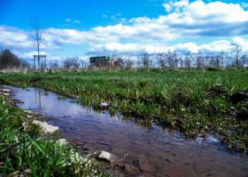 View of field against cloudy sky