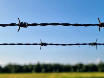 Close-up of barbed wire fence against sky