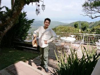 Portrait of young man standing on table against trees