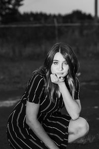 Portrait of beautiful woman crouching on road at dusk