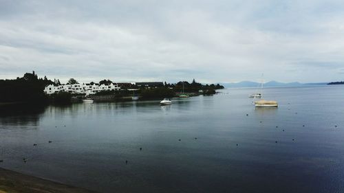 Boats in sea against cloudy sky