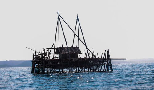 Wooden structure in sea against clear sky